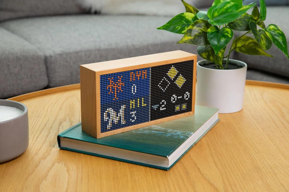 Tidbyt on coffee table displaying the score for a baseball game