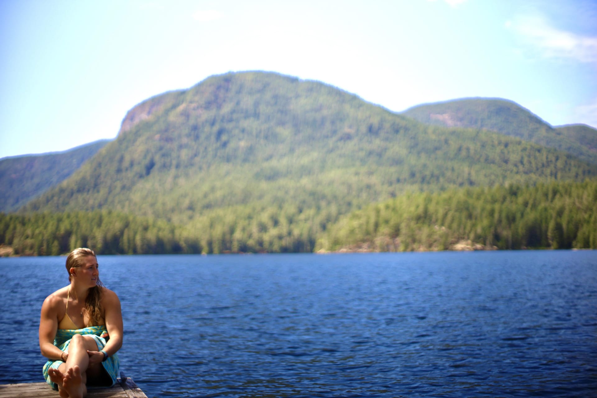 Mackenzie Stewart sitting alone on a dock over a lake