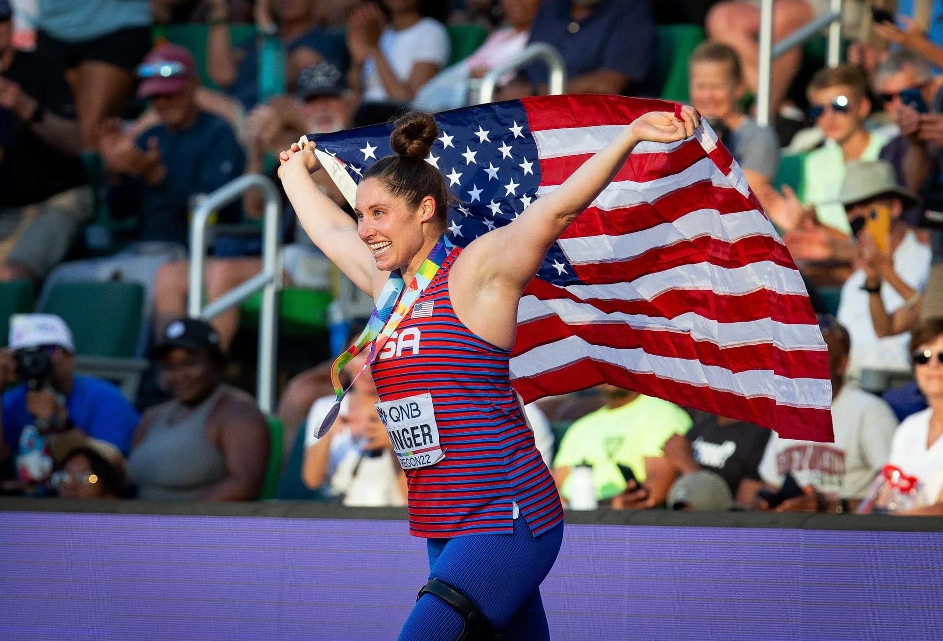 Kara wearing a silver medal and holding the US flag behind her at the Olympics