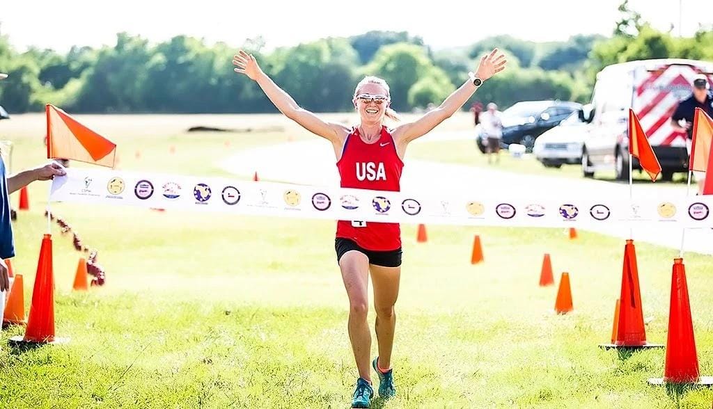 Schultz breaking ribbon at a race wearing USA jersey