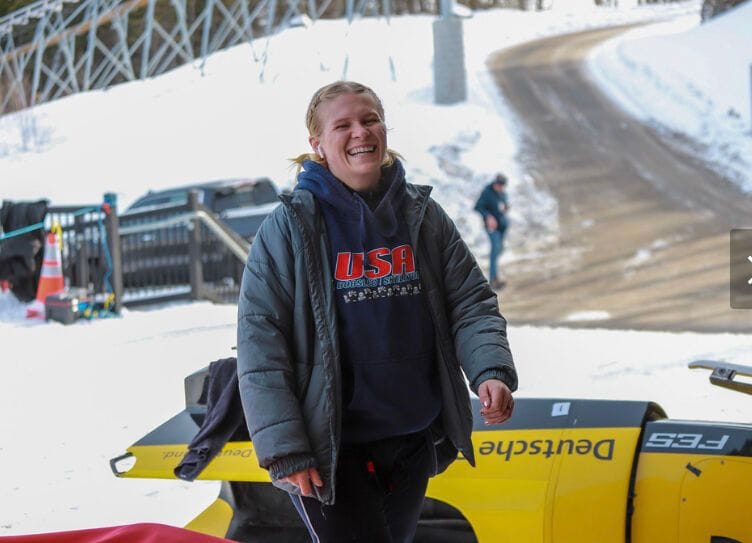 Malory smiles in a USA hoodie by a snowy access road