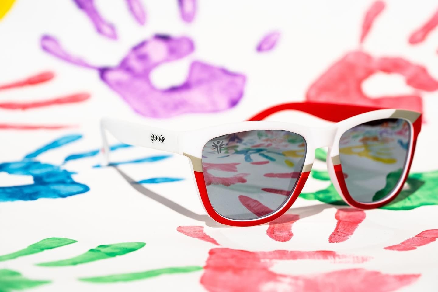 goodr sunglasses on a background of colorful paint handprints
