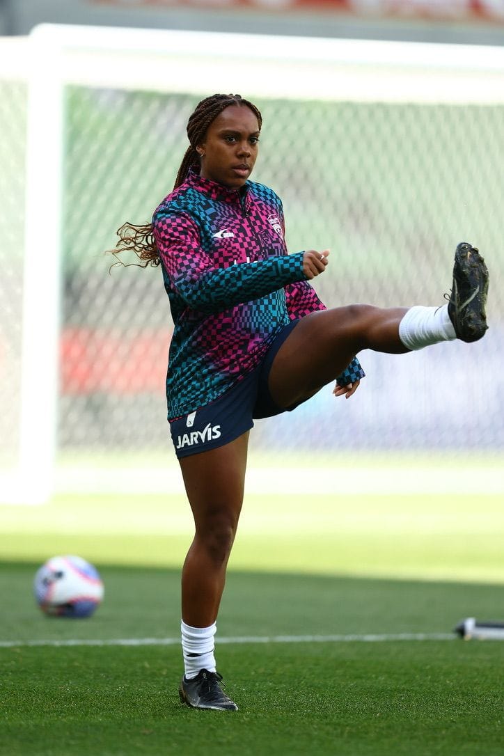 Mariah practices a high kick on the soccer field