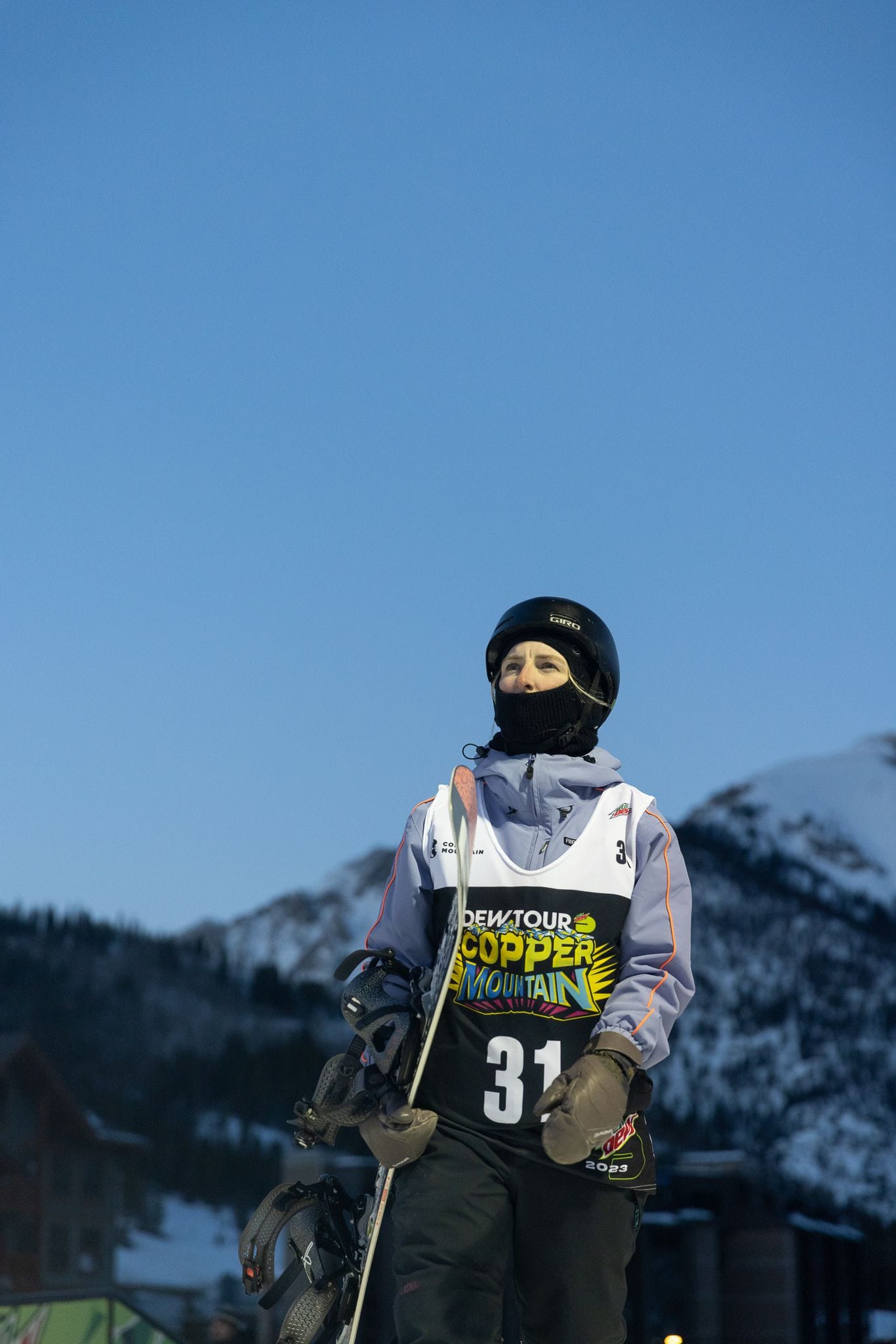 Madison carries snowboard with mountainous background