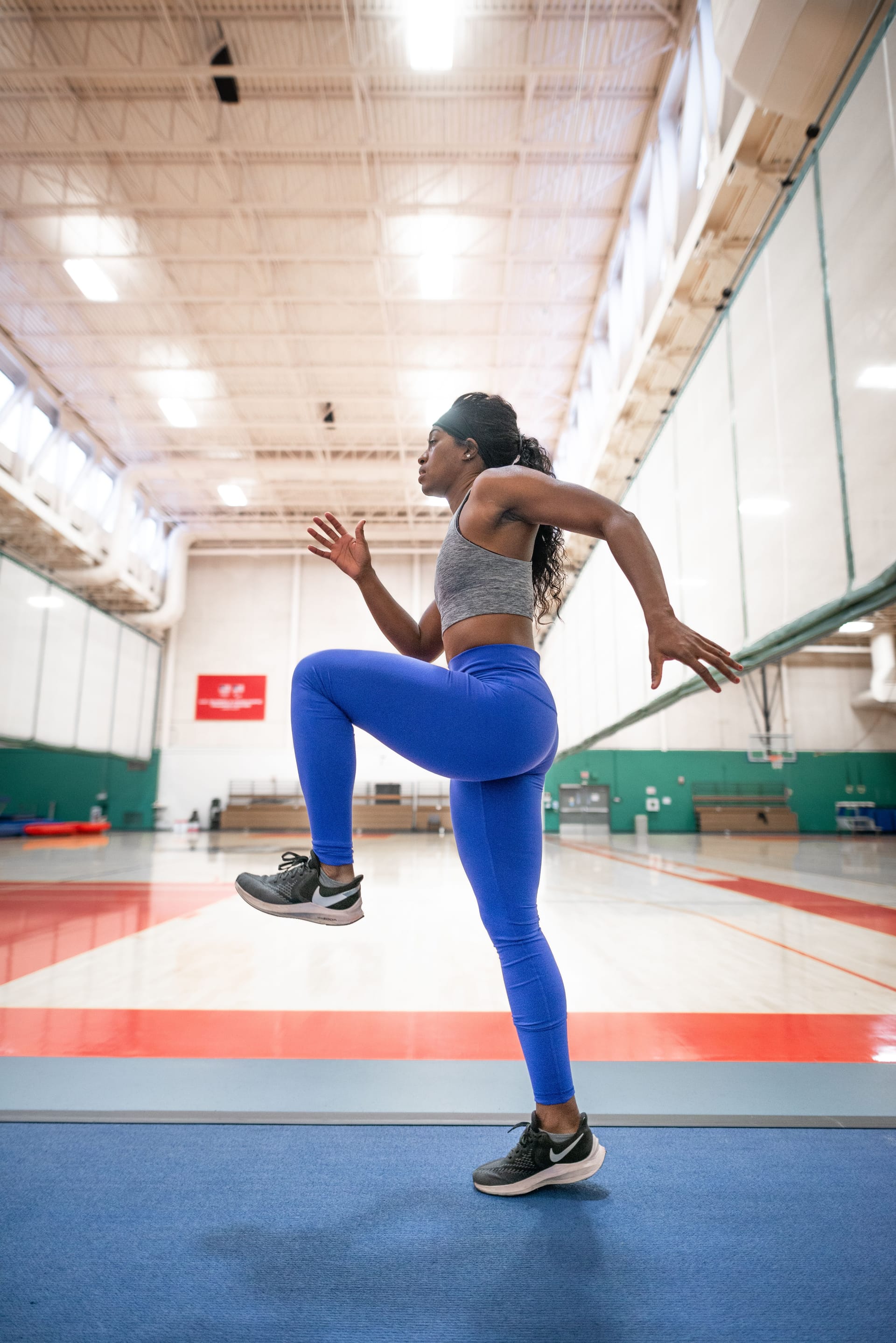 a woman does standing knee ups in a gymnasium