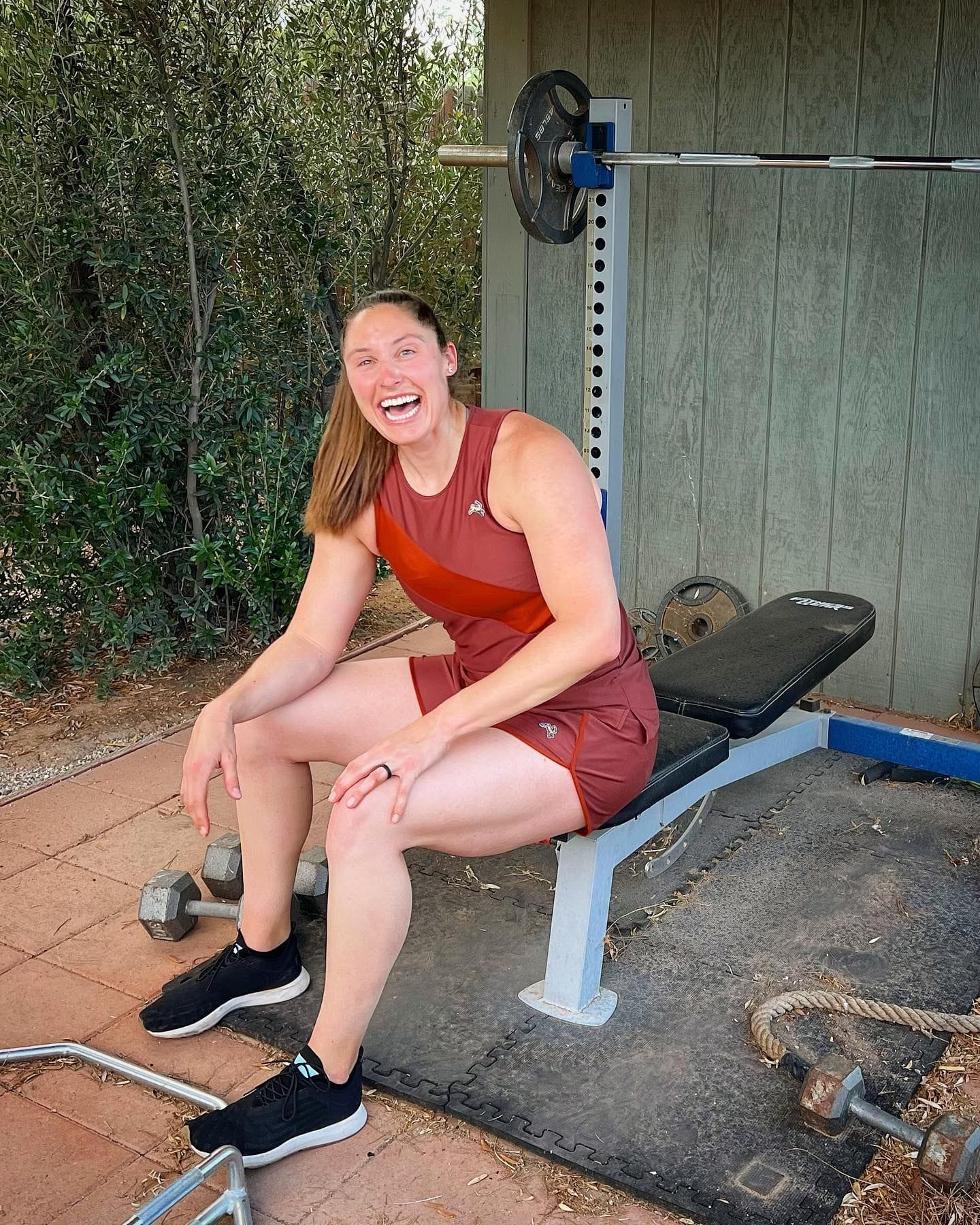 Kara laughing on the bench of her backyard weight lifting setup