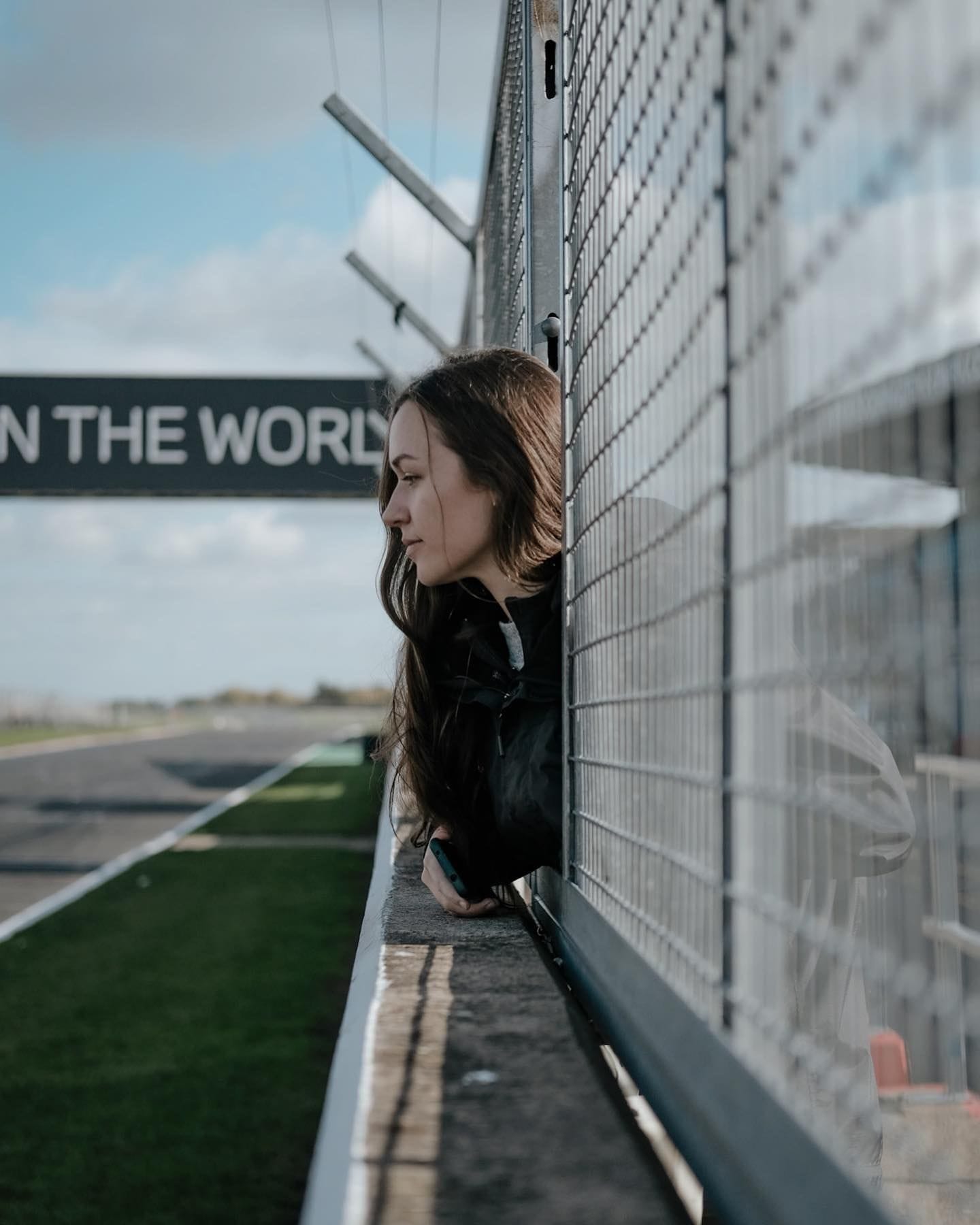 Erika leans on the stadium barrier looking over the race track