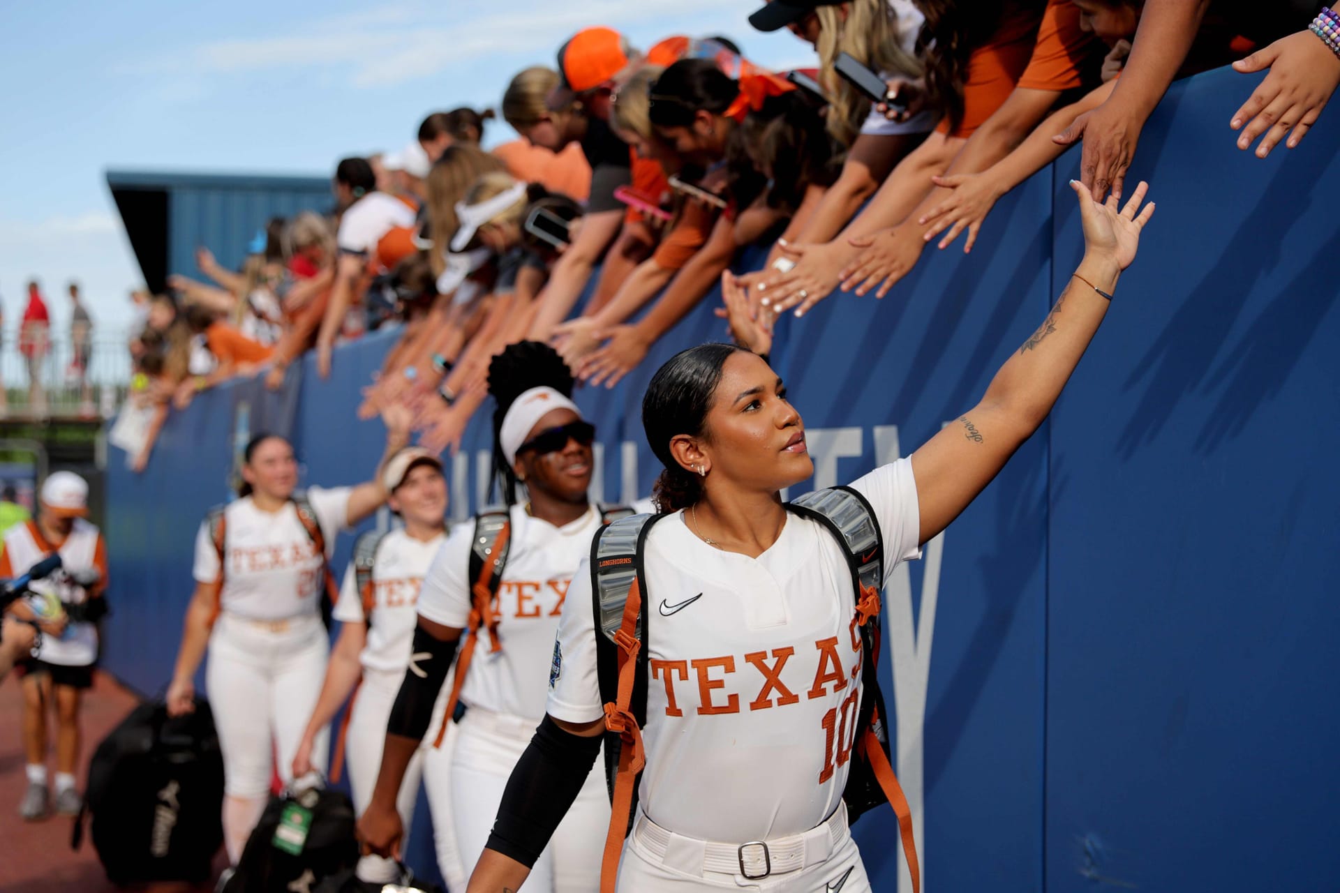 Softball team high fives fans before game