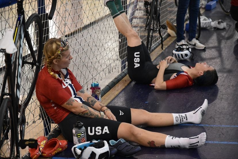 Mallory rests with other competitors against a chainlink fence at an event
